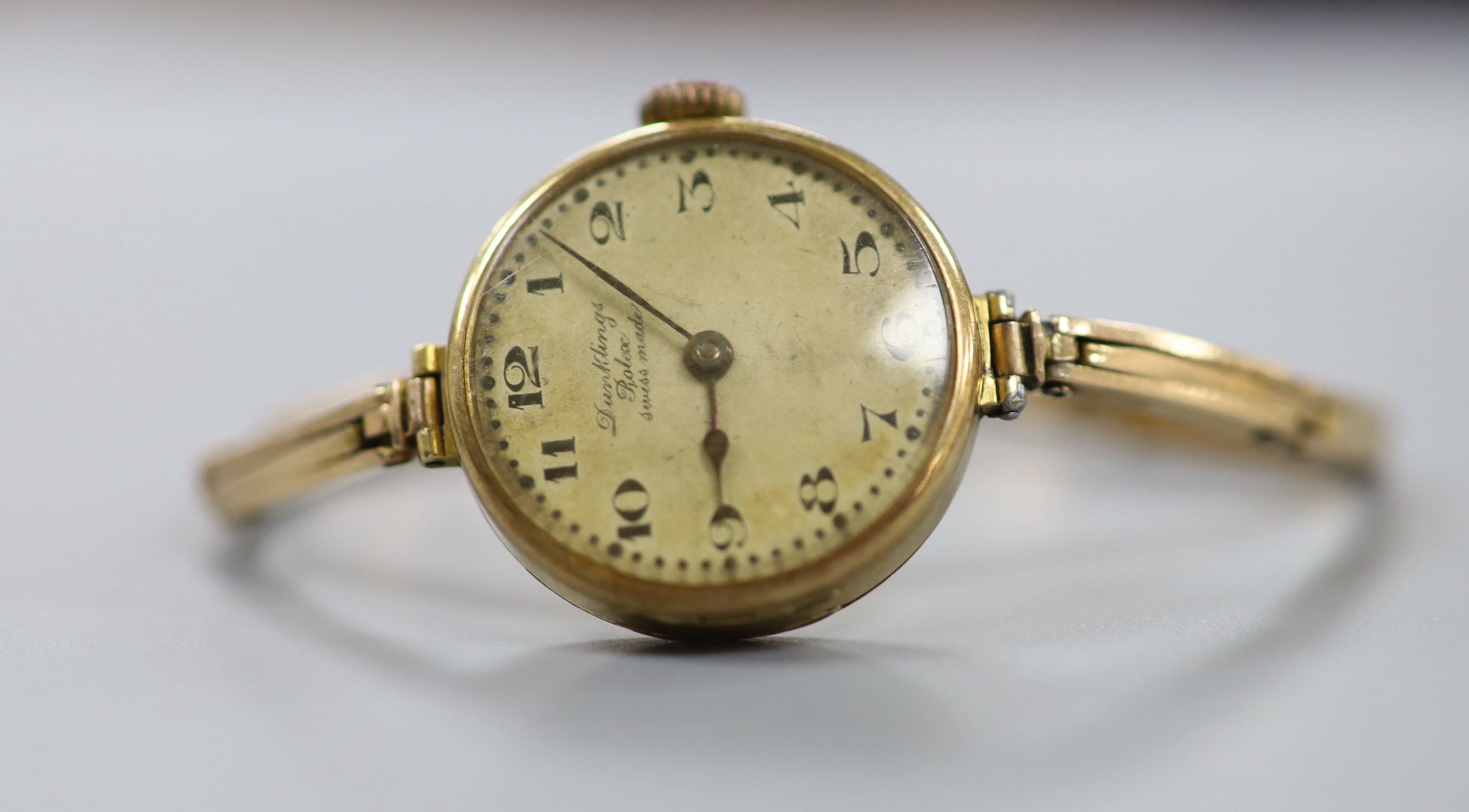 A lady's early 1920's 18ct gold Rolex manual wind wrist watch, with case back inscription, on a flexible yellow metal bracelet stamped 'W15D', case diameter 23mm, length 16.3cm, gross weight 20 grams.